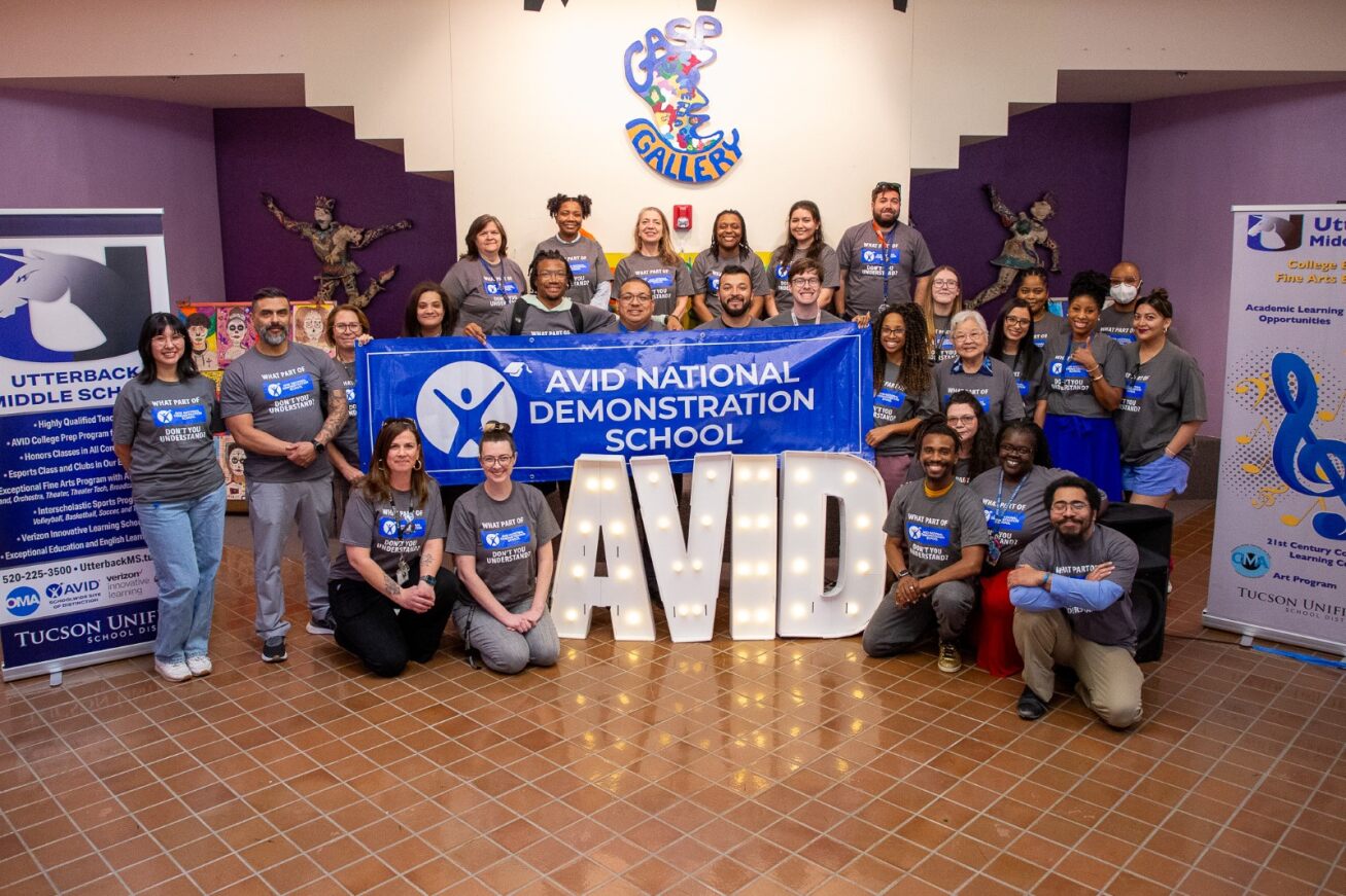 Utterback teachers gather around a light up AVID sign and a banner reading AVID National Demonstration School