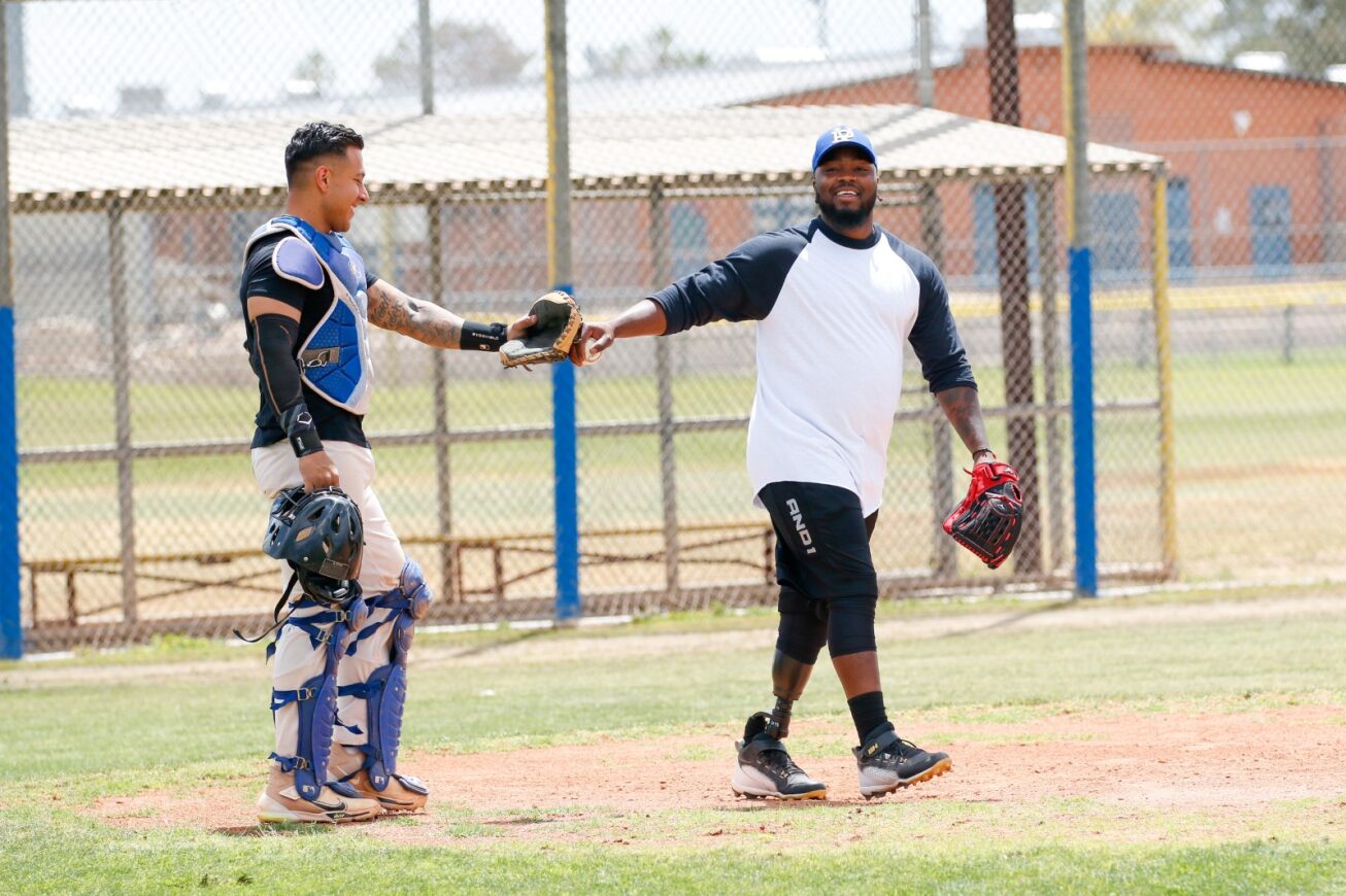 Two alumni players fist bump on the baseball field