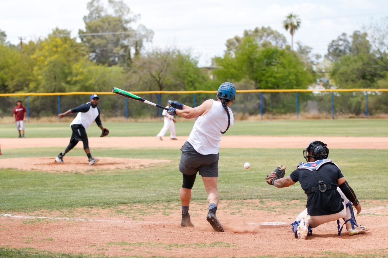 A player swings his bat at the ball while the catcher prepares to catch it