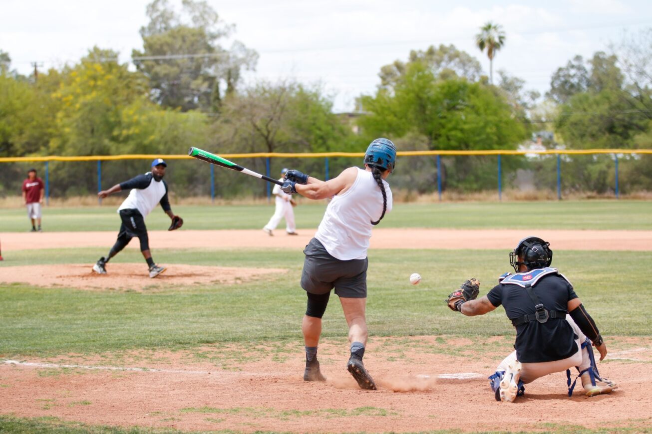 A player swings his bat at the ball while the catcher prepares to catch it