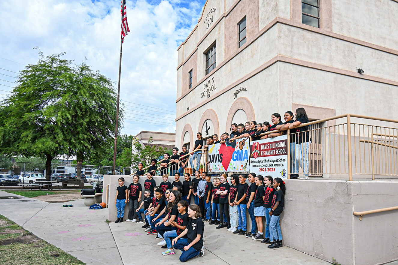 The Davis mariachi stands in front of the school with a sign that says "Davis Loves GMA"