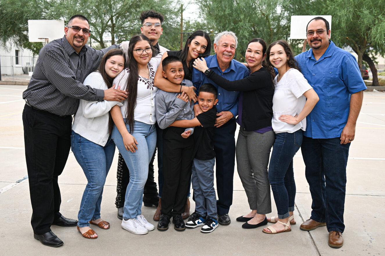 The four generations of the Valenzuela mariachi family pose together and smile.