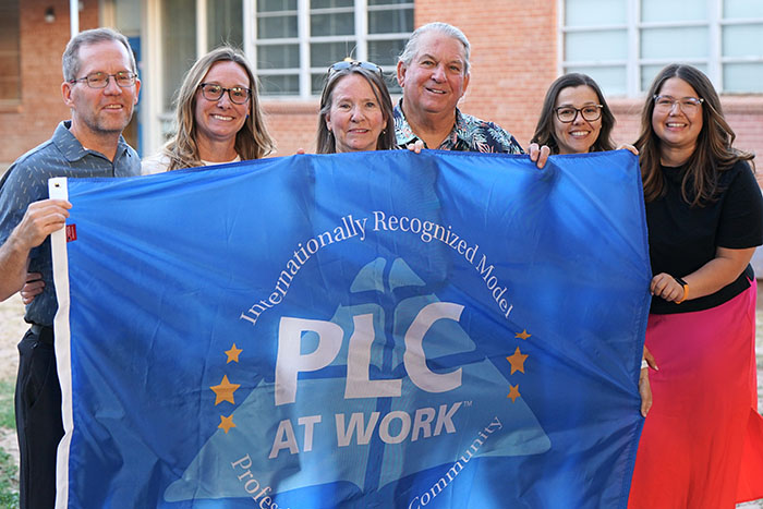 A group of people hold up a Model PLC blue banner