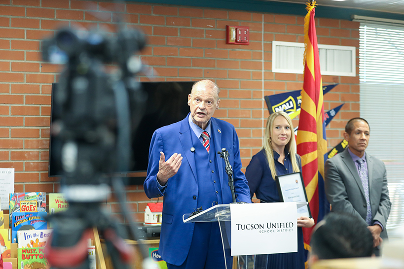 A man in a blue suit addresses the audience