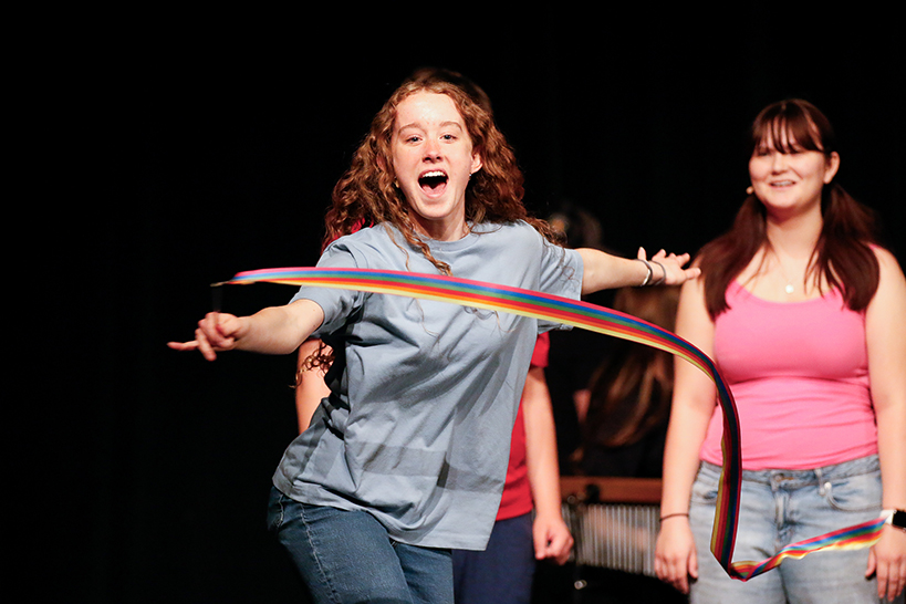 A girl, center, twirls a colorful ribbon as another girl behind her smiles