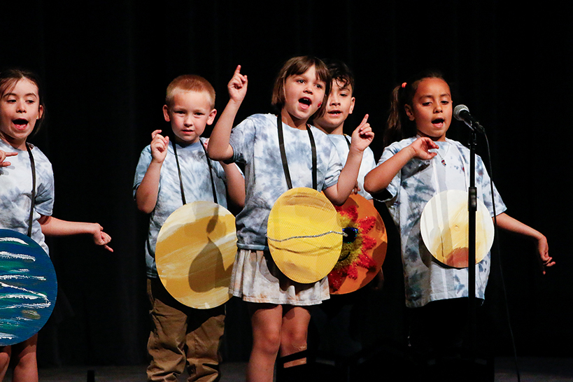 Young students act out a scene as the planets of the solar system