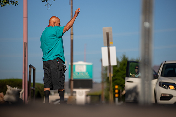 A man in an aqua shirt waves to families in the drop-off line
