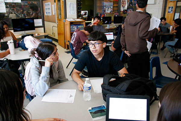 Students gather around a table in a classroom