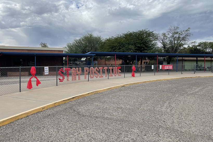 A message of Stay Positive on the fence around the school entrance