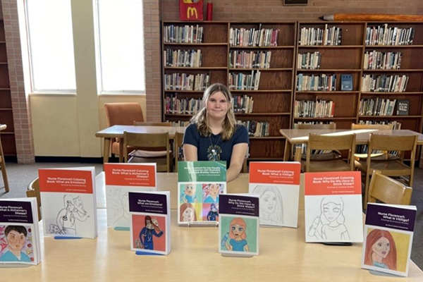 Anastasia sits behind a selection of donated books her club collected