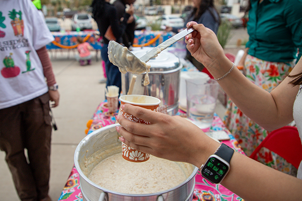 A woman scoops up some corn stew into a cup