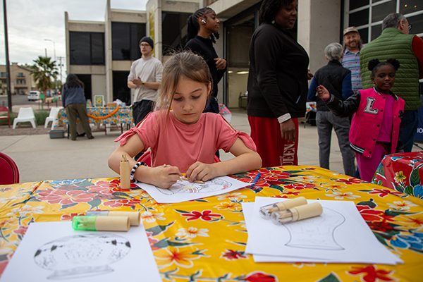 A little girl colors in a coloring page