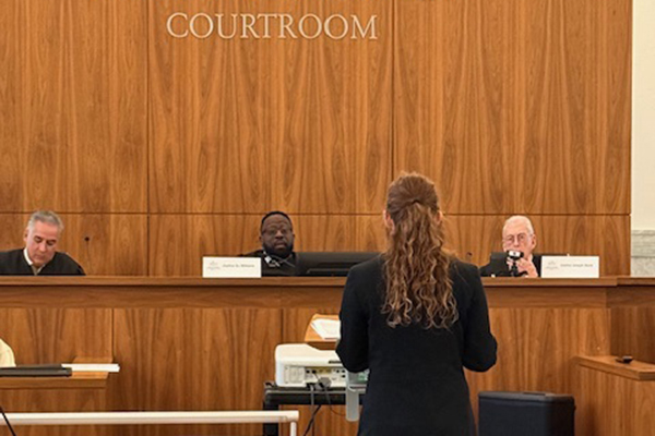 A young woman with red curly hair faces the panel of judges
