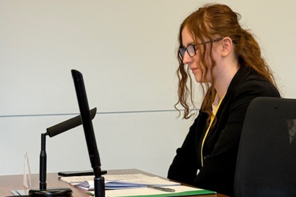 A young woman with red curly hair and glasses prepares her arguments