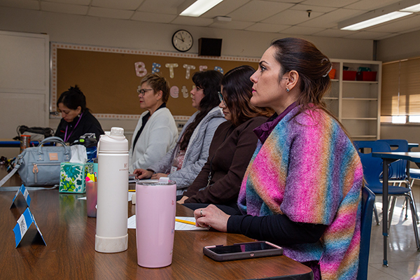 Women sit at a table in a classroom