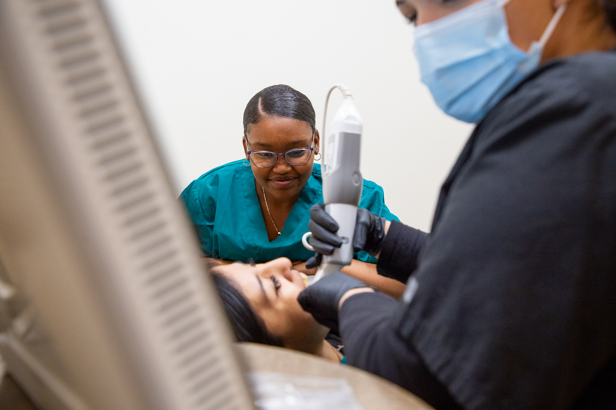 Dental assisting students perform a scan on a student's mouth