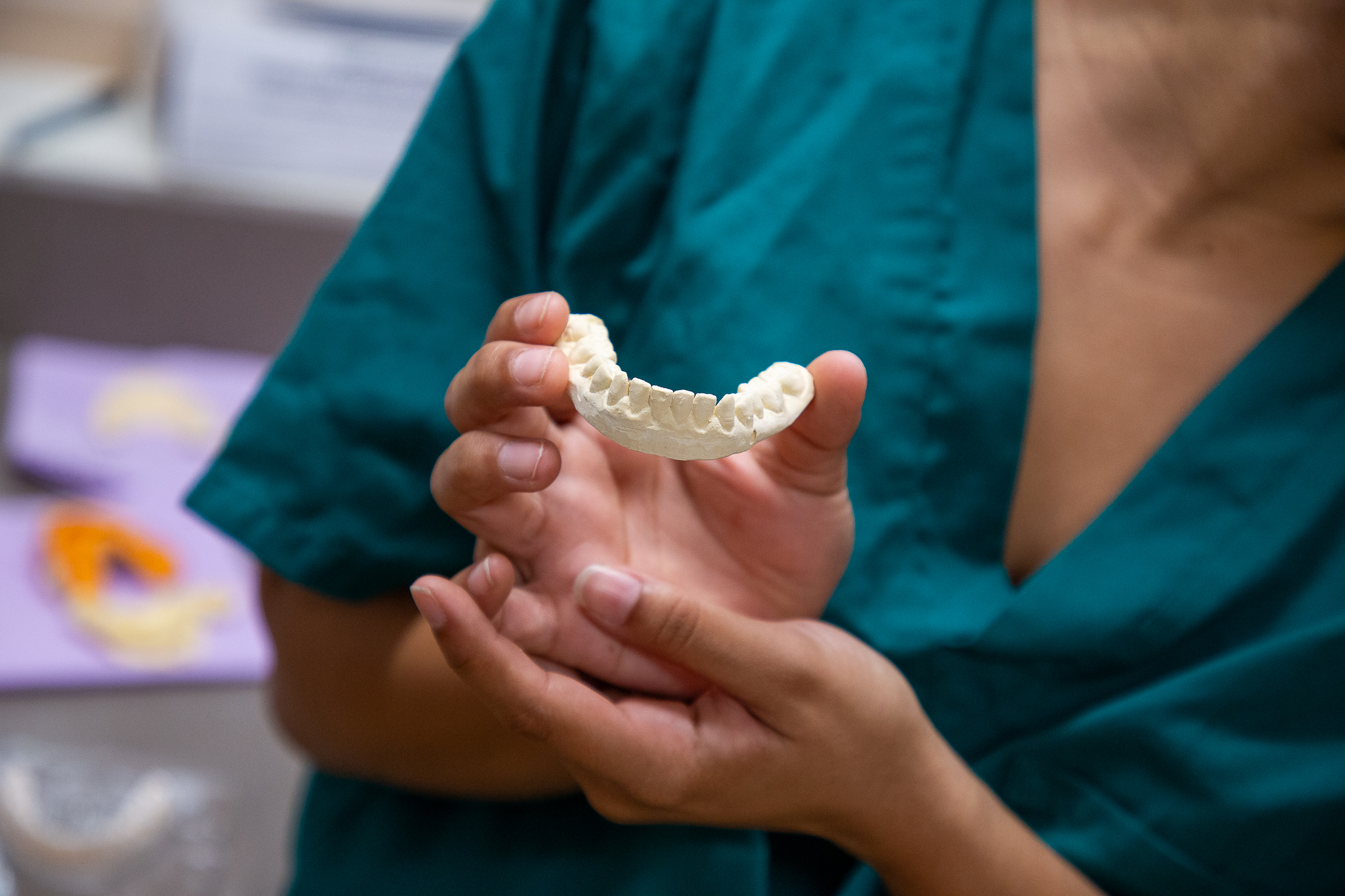 A dental student holds up a clay model of a mouth