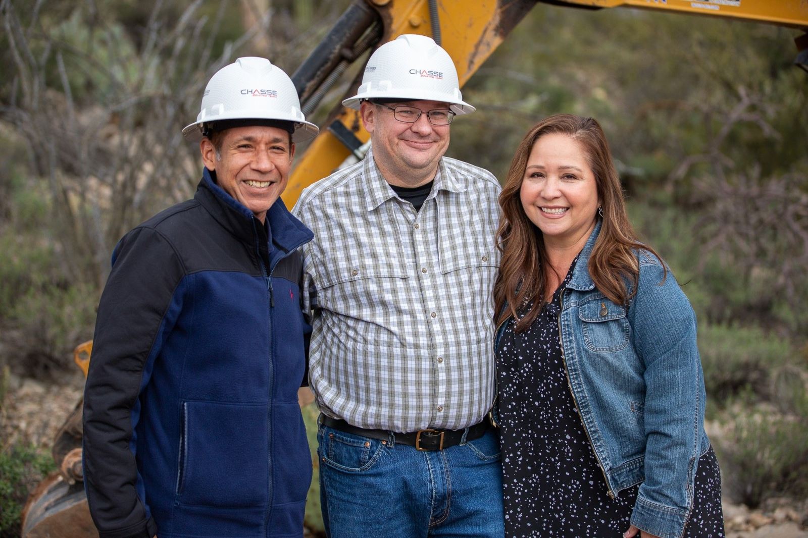 Dr. Trujillo smiles in a hard hat next to a man and a woman at the ribbon cutting at Camp Cooper